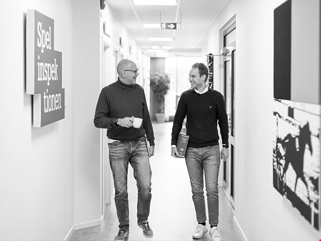 Två män som går i en korridor och pratar glatt med varandra
